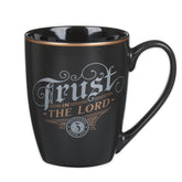 Taza cerámica inspiradora de Christian Art Gifts con acabado mate negro y detalles dorados para disfrutar en casa.