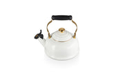 Hervidor Le Creuset con esmalte blanco y detalle dorado para hervir agua rápidamente.