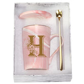 Taza WENSSY rosa de 14 onzas con letra H y flor, ideal para tu ritual matutino.