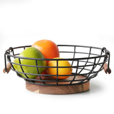 Cesta Wildmos de fruta con alambre negro y base de acacia, exhibe frutas frescas.
