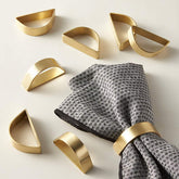 Anillos de servilleta dorados mate Wonlex en semicírculo para una mesa elegante.