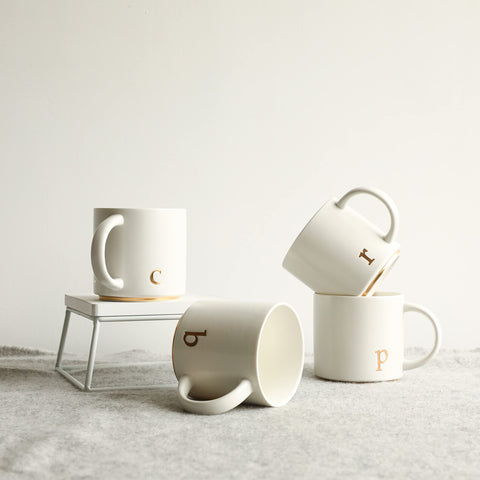 COLLECTIVE HOME, diseño de monograma dorado en taza cerámica