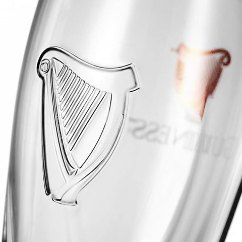 Arpa grabada en el dorso de un vaso Guinness con diseño icónico.