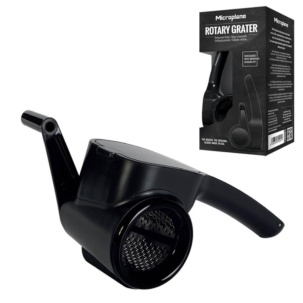 Microplane gratera manual rotativa negra en uso para parmesano directo en la mesa, fácil de limpiar