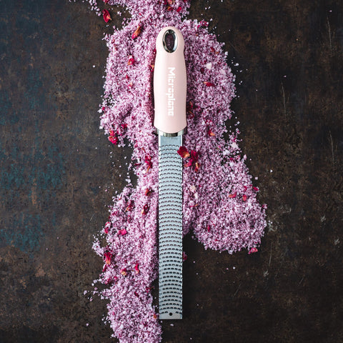 Microplane rallador rosado rallando chocolate para postres y bebidas.