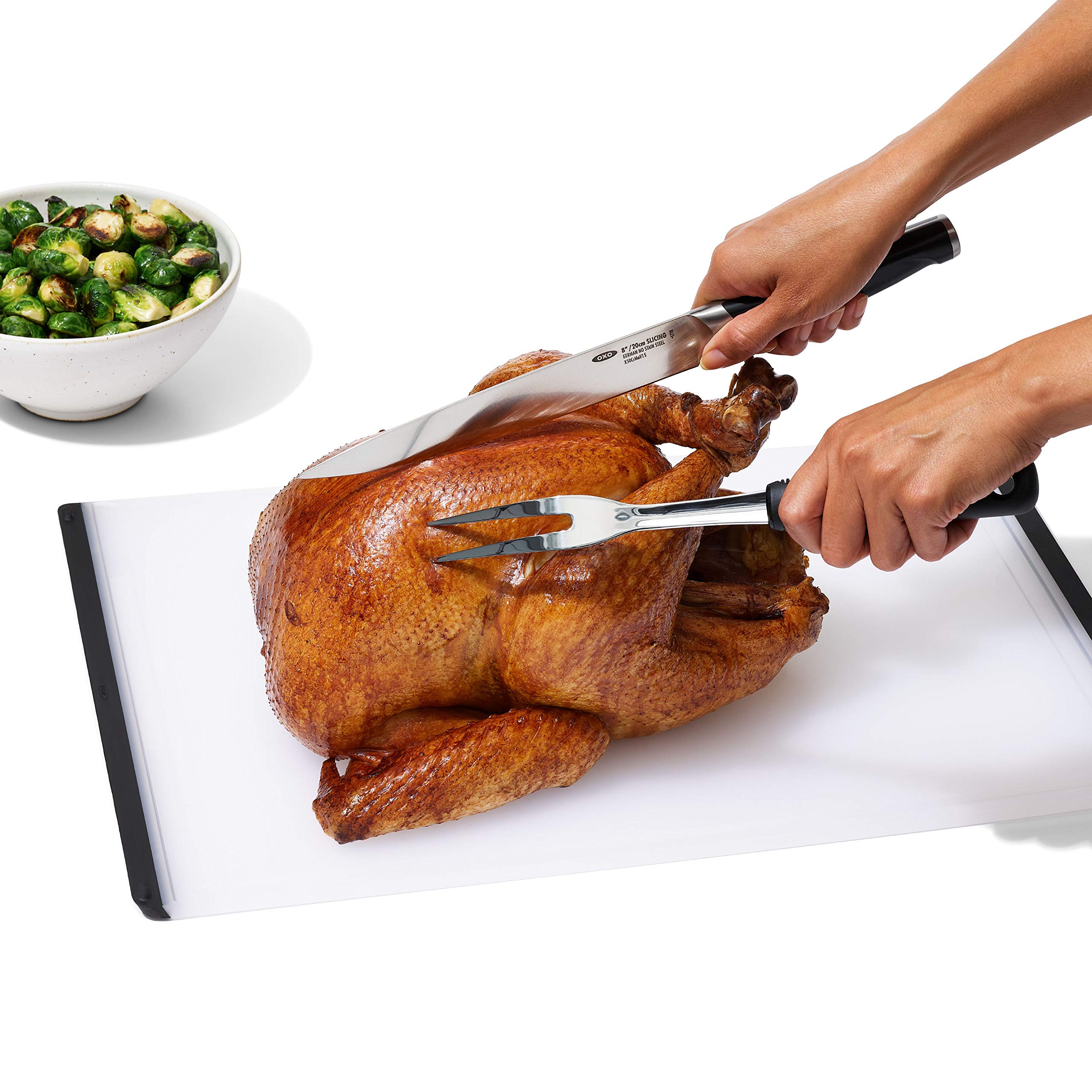 Tenedor compacto para cortar carne OXO, acero inoxidable, guía estable para porciones.