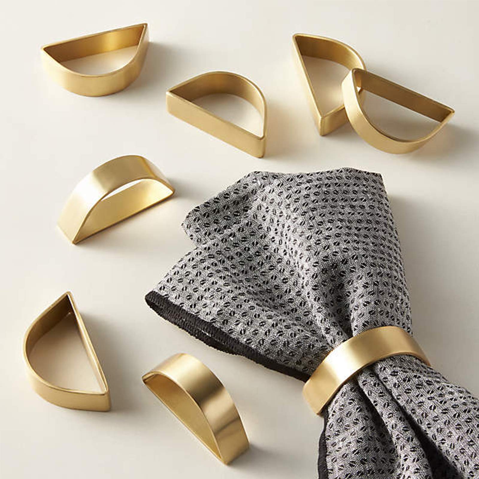 Anillos de servilleta dorados mate Wonlex en semicírculo para una mesa elegante.